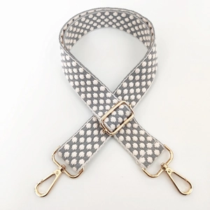 Adjustable woven bag strap with grey and white polka dots and gold metal buckles
