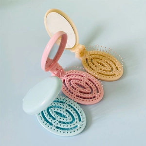Portable folding hairbrush with mirror in beige, pink and blue for travel massage