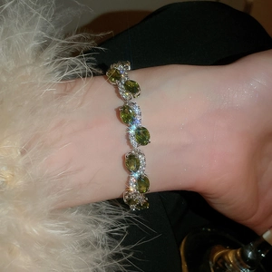 Close-up of olive green oval zircon bracelet with sparkling diamond-set metal links