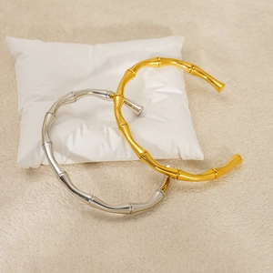 Detail of gold and silver bamboo style bangles displayed on a soft white cushion
