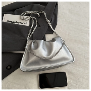 Close-up of silver pleated cloud bag with metallic chain strap on a stylish background