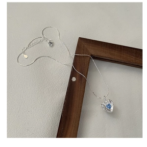 Macro shot of S925 silver necklace with textured blue heart zircon pendant on wood