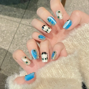 Handmade press-on nails with blue cat-eye effect and green emerald rhinestone accents
