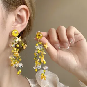 Detail of floral tassel earrings with yellow dried flowers and delicate beaded strands