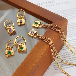 Golden chunky lock earrings with purple and green zircon stones on magazine background