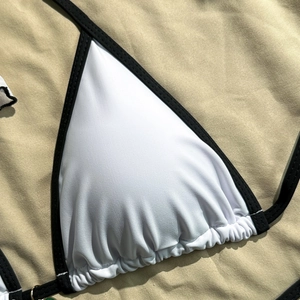 Detail of white triangle bikini top with black trim and pleated texture for women
