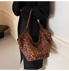 Close-up of leopard print tote bag with brown leather handles and knotted strap detail