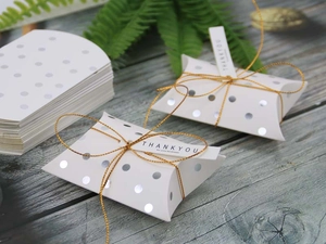 Assembled white pillow gift box with silver dots and Thank You tag on wood surface