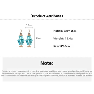 Detail of fish-shaped earrings with blue shells, evil eye motif, and 11x3.5cm dimensions