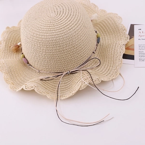Detail of summer straw hat for girls with wavy brim, colorful beads and a delicate bow
