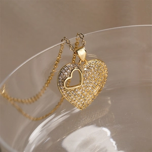 Detailed view of gold heart pendant with micro-paved zircons on glass edge