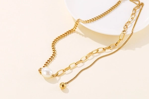 Detail of gold spliced chain necklace featuring a baroque pearl and polished gold bead
