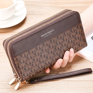 Close-up of brown long wallet with vintage monogram pattern and dual gold zippers