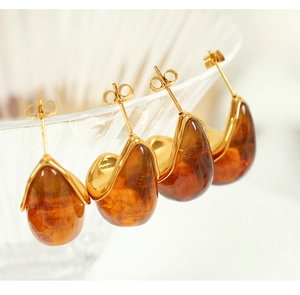 Detail of amber teardrop earrings with 18K gold-plated borders on glass