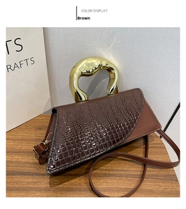 Detail of coffee crocodile pattern handbag with unique gold geometric metal handle