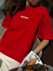 Dettaglio della t-shirt rossa 100% cotone con stampa Assertive bianca e trama morbida