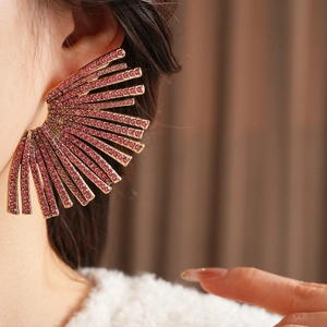 Macro view of fan-shaped gold earrings featuring dense pink crystal embellishments
