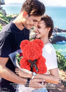 Romantic couple holding a red PE rose bear gift in a scenic coastal outdoor setting