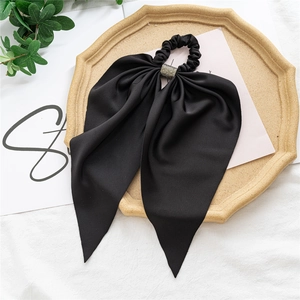 Detail of black silk bow scrunchie with rhinestone buckle on elegant beige tray