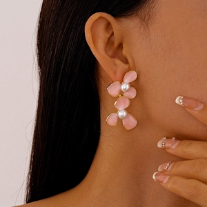 Detailed close-up of pink flower petal earrings with white pearls on a female model