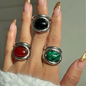 Detailed view of model wearing three vintage rings with oval red, black and green stones