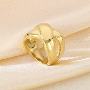 Macro shot of chunky gold criss-cross ring on elegant champagne satin fabric background