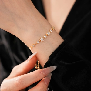 Close-up of a gold-plated bracelet with sparkling star zircon stones on a model's wrist