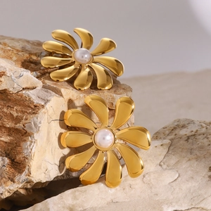 18k gold plated sunflower stud earrings with pearl center on natural stone backdrop