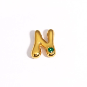 Détail du pendentif lettre N dorée orné d'une petite pierre gemme cœur verte
