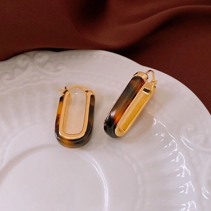 Orecchini a forma di U placcati in oro con stampa leopardata su piatto in ceramica bianca