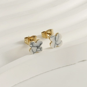 Macro view of gold clover earrings with white marble texture on a wavy display