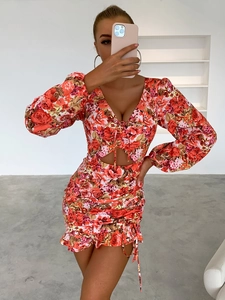 Gros plan sur l'élégant col en V et le motif floral orange de la robe à manches longues
