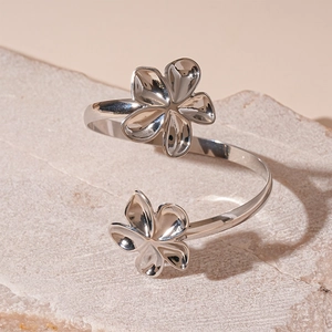 Gros plan d'un bracelet ouvert argenté avec motif floral creux sur socle en pierre