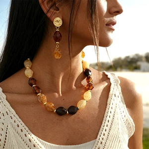 Detail of vintage amber acrylic beaded necklace and matching gold earrings on model