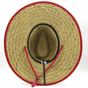Dettaglio di cappello di paglia con bordo rosso e sottogola regolabile in stile etnico