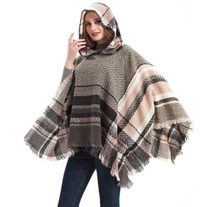 Close-up of thick plaid knit poncho with irregular hemline and tassel details