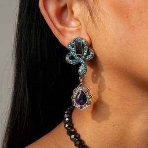 Close-up of vintage snake-style earring with large purple teardrop crystal and colorful stones