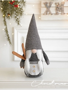 Close-up of Nordic Christmas gnome with knitted hat and wooden skis on festive background