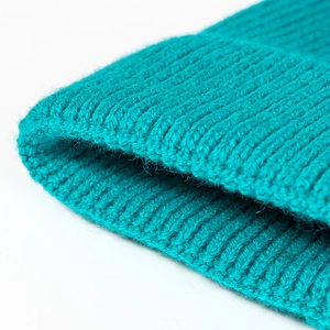 Teal ribbed knit beanie cap for winter with soft elastic texture on white background