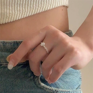 Detail of s925 silver ring with oval white gemstone on hand with minimalist chain band