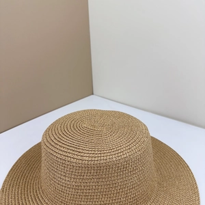 Close-up detail of the fine woven texture on the flat top of a natural brown straw hat