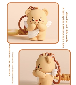 Close-up of yellow angel bear keychain with white wings and brown woven strap