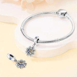 Detailed close-up of a silver snake chain bracelet featuring sun and moon charm pendants