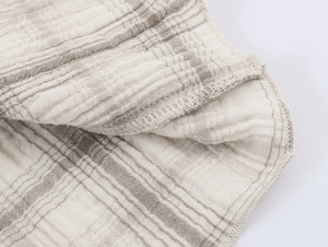 Detailaufnahme der sauberen Overlock-Naht und beige gestreifter Textur am Damenkleid