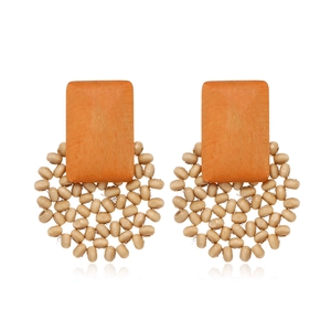 Detail view of retro geometric wooden earrings with orange blocks and beige woven beads