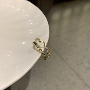 Detailed close-up of a gold-plated twisted wave ring with micro-set zircon accents