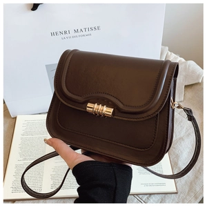 Détail d'un sac besace vintage en cuir marron foncé avec fermoir tournant doré texturé