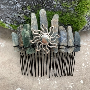 Detailed view of raw blue crystals and silver sun pendant on a black metal hair comb