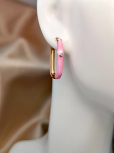 Detail of pink enamel rectangular hoop earring with zircon on a champagne silk background
