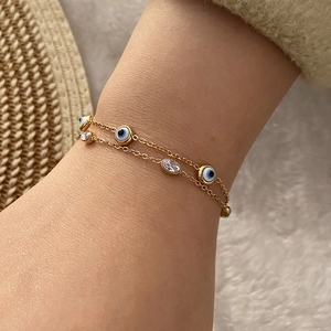 Nahaufnahme eines doppellagigen goldenen Evil-Eye-Armbands mit klaren Zirkon-Steinen